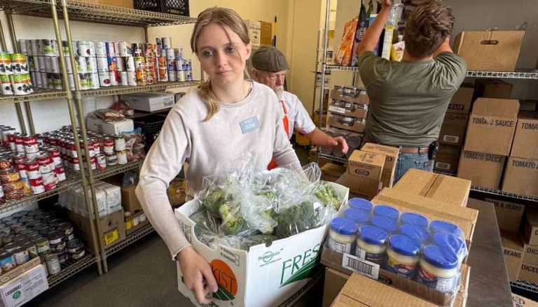 une jeune qui aide à trasnporter une caisse de légumes